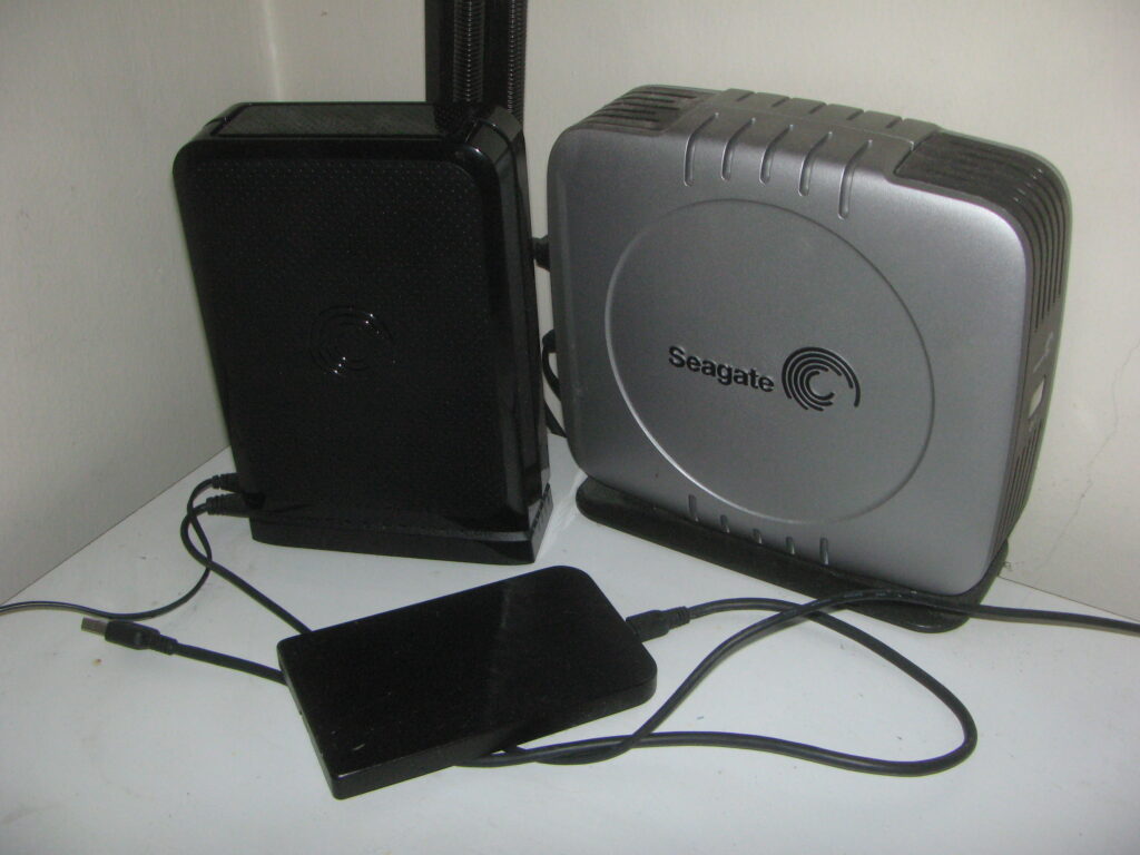 Three external hard drives on a desk representing backup storage.