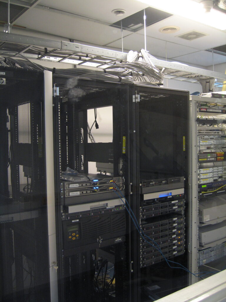 Black server cabinets with rack-mounted equipment and cables routed overhead.
