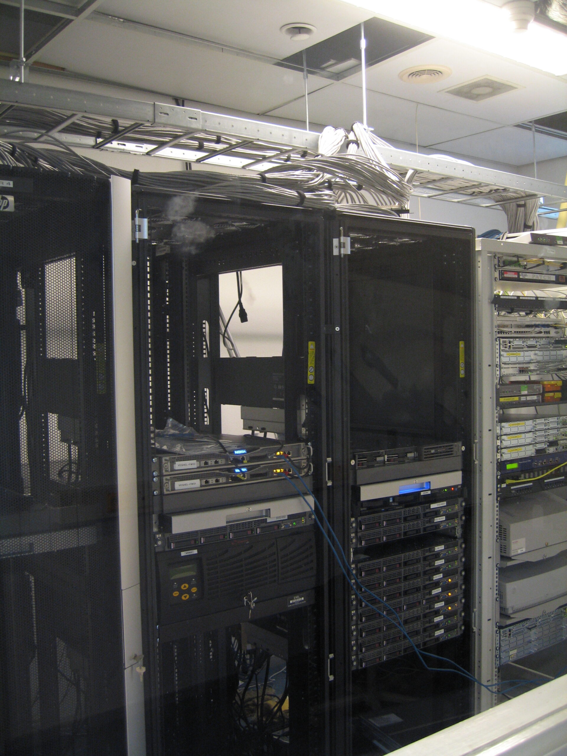 Black server cabinets with rack-mounted equipment and cables routed overhead.